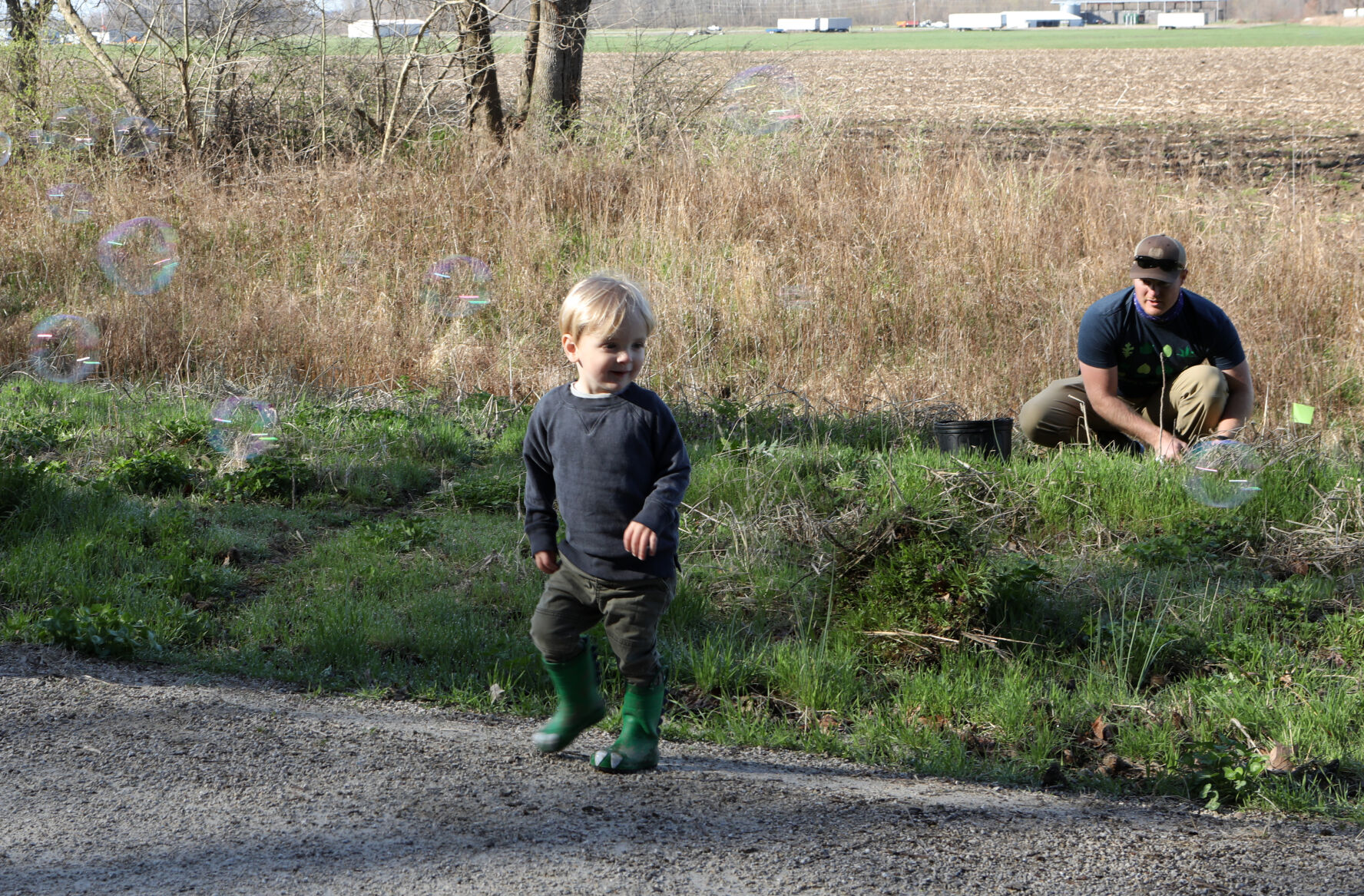 Eli Yager chases bubbles while Zach Yager plants a tree